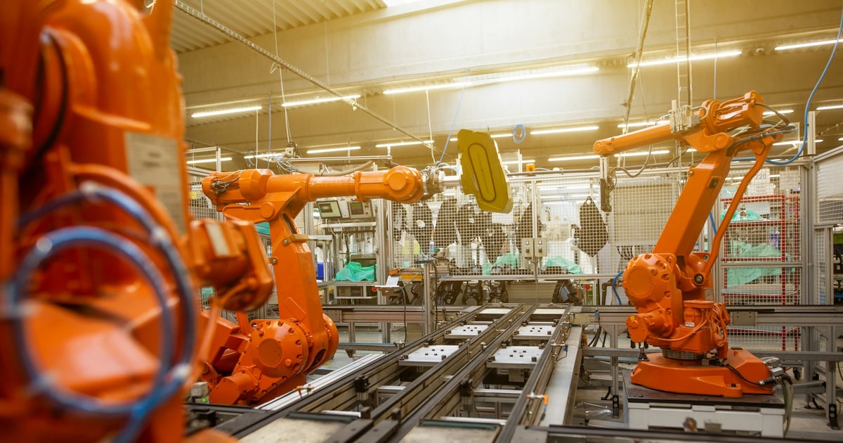 Orange industrial robot arms working along a factory production line